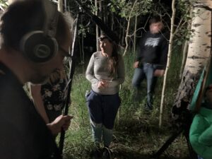 Photo: Outdoors, in the woods at night a crew plans a film scene.